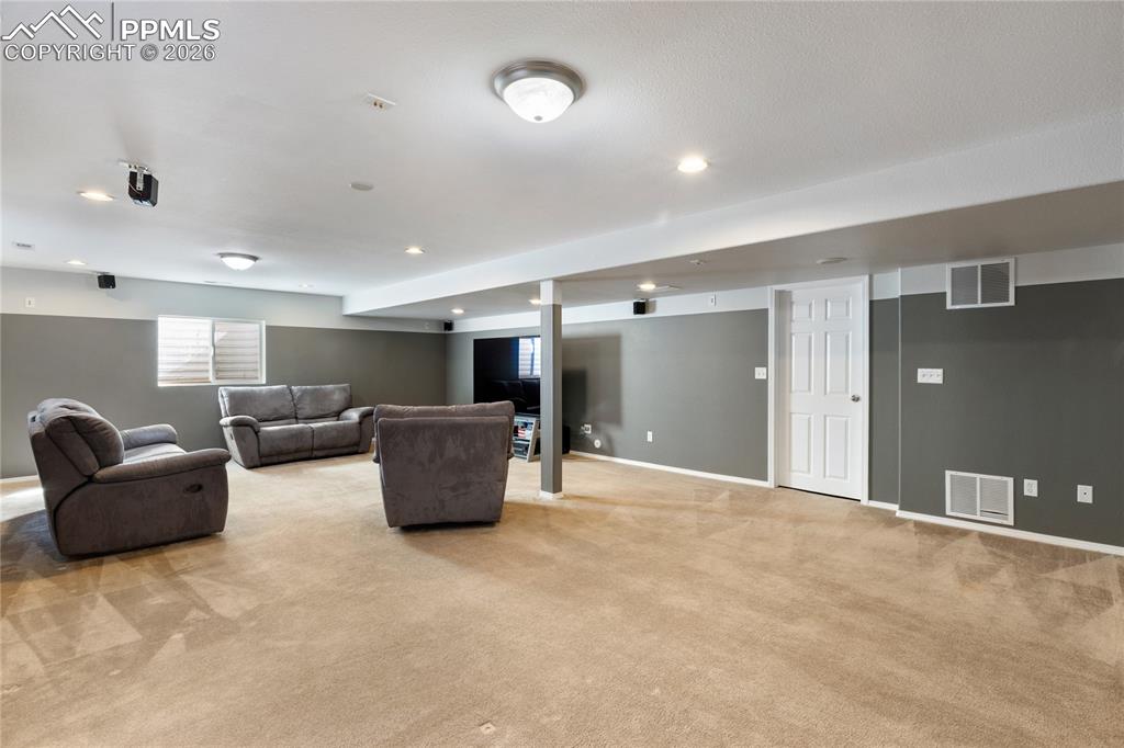 Image 33 of 36: Living area with light carpet and recessed lighting