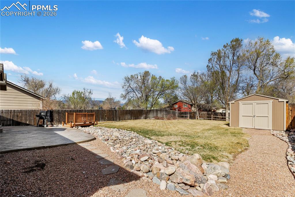 Image 4 of 36: Fenced backyard with a storage shed and a deck