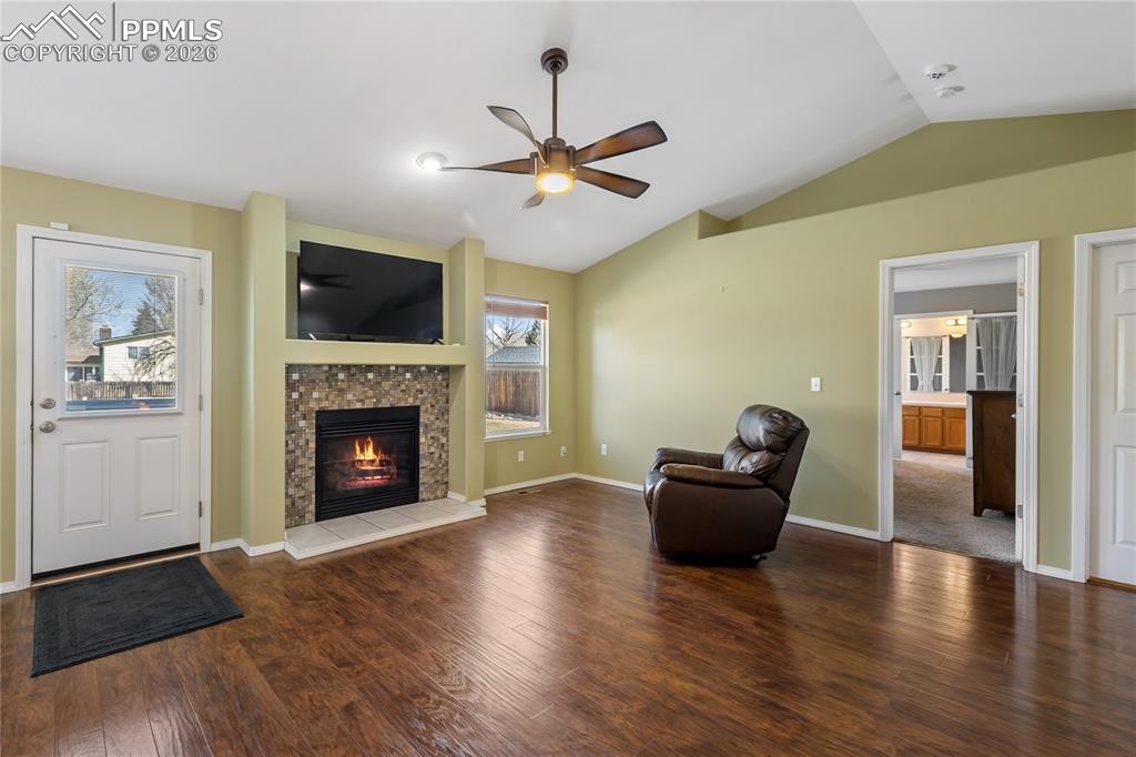 Image 7 of 36: Unfurnished room featuring dark wood finished floors, a ceiling fan, a fire