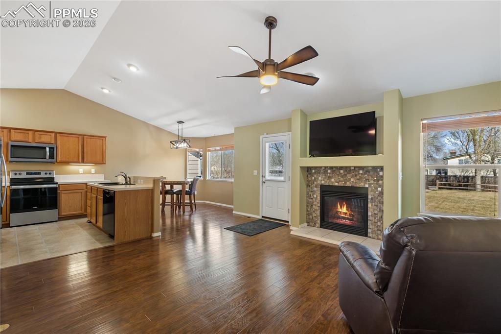 Image 8 of 36: Living area featuring light wood finished floors, a ceiling fan, and a fire