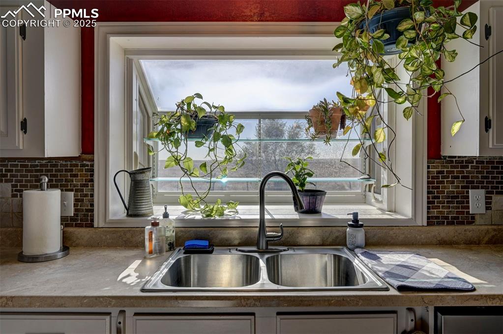 Image 12 of 31: Kitchen with white cabinets, tasteful backsplash, and light countertops