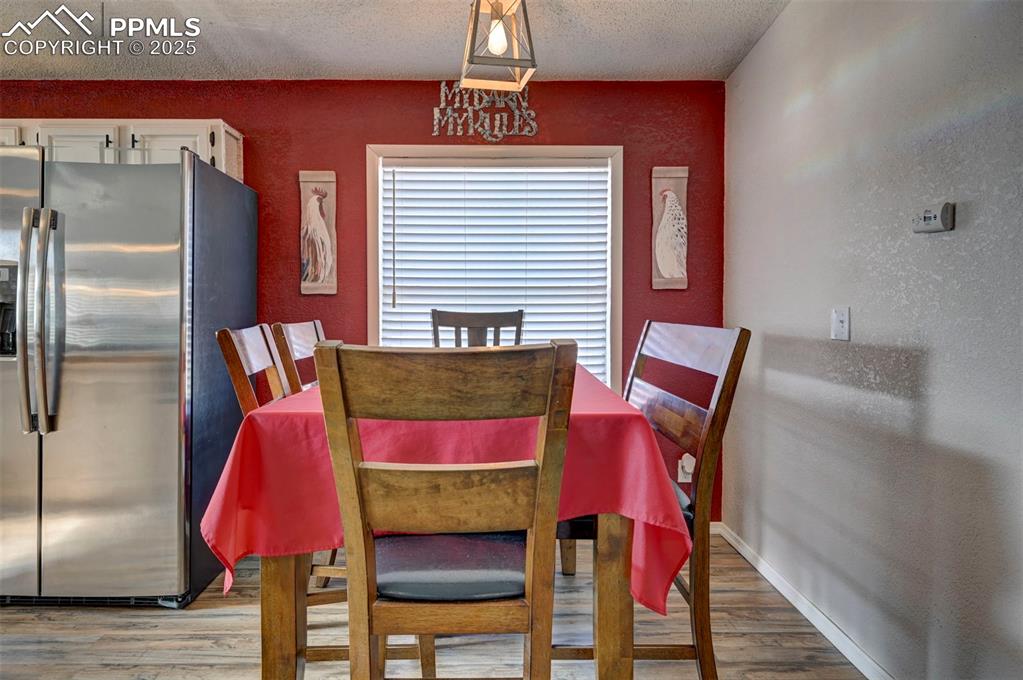 Image 13 of 31: Dining space with light wood-type flooring, a textured wall, and a textured