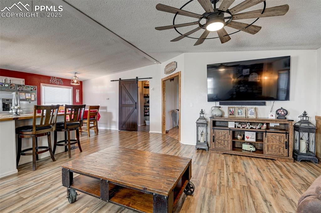 Image 14 of 31: Living area featuring a barn door, a textured ceiling, light wood-type floo