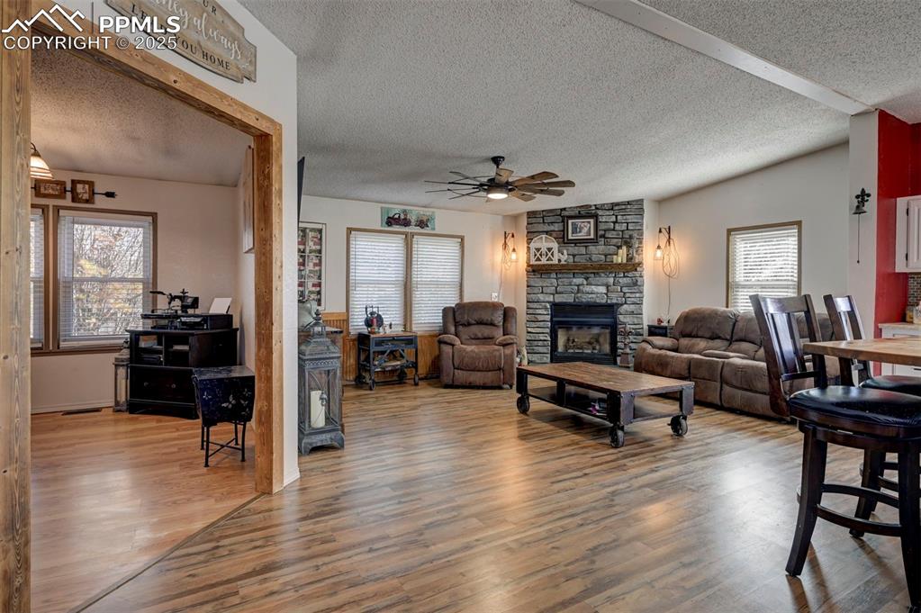 Image 15 of 31: Living room with a textured ceiling, a stone fireplace, light wood finished