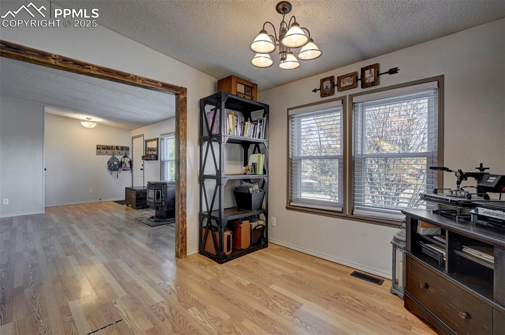 Image 18 of 31: Home office with a textured ceiling, a wood stove, light wood-style floorin