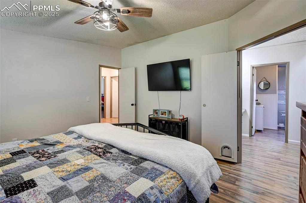 Image 19 of 31: Bedroom with a textured ceiling, light wood finished floors, and ceiling fa