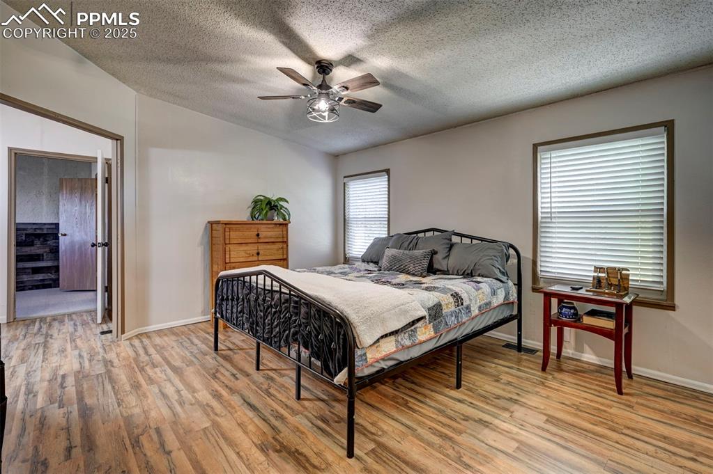 Image 20 of 31: Bedroom with light wood-style flooring, a textured ceiling, and ceiling fan