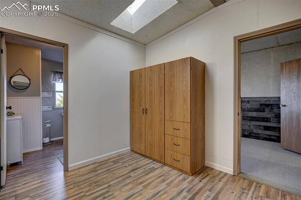 Image 22 of 31: Bedroom featuring light wood-style floors, a skylight, a textured ceiling,