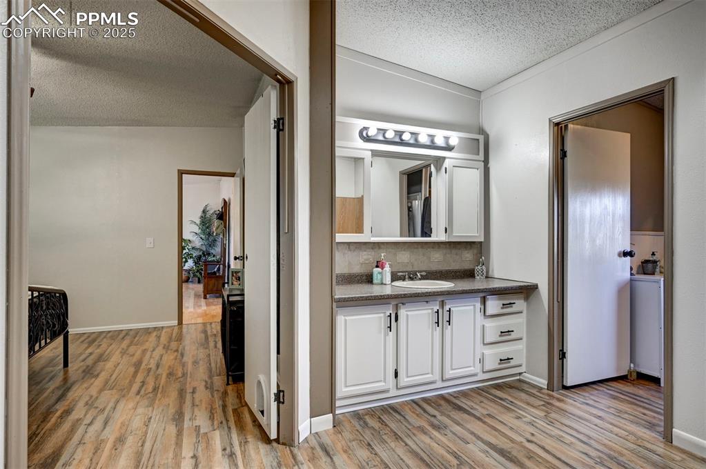 Image 23 of 31: Bathroom with a textured ceiling, light wood-style floors, vanity, and deco