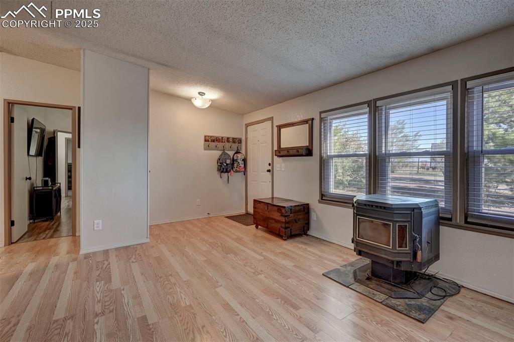 Image 7 of 31: Entrance foyer with a wood stove, a textured ceiling, and light wood-style