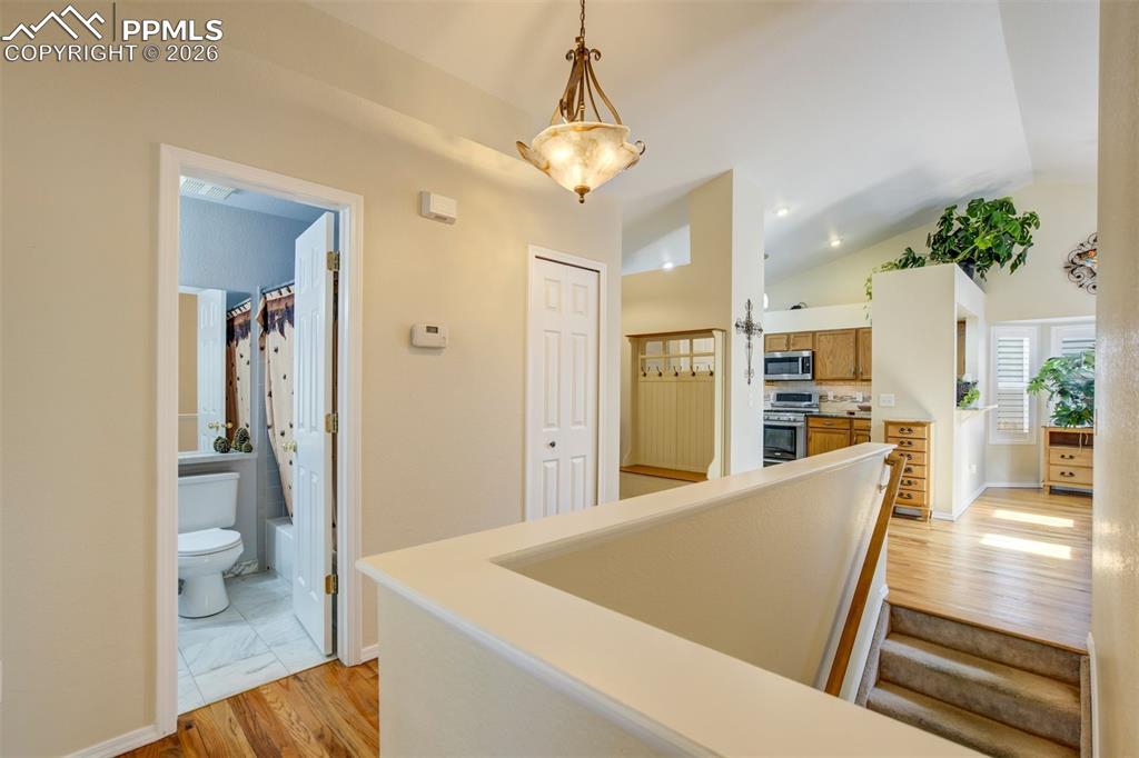 Image 19 of 50: Hallway with warm hardwood floors and an open-concept layout that immediate