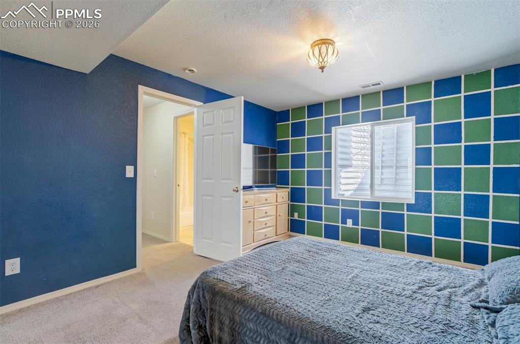 Image 37 of 50: This spacious bedroom stands out with its bold designer accent wall and gen