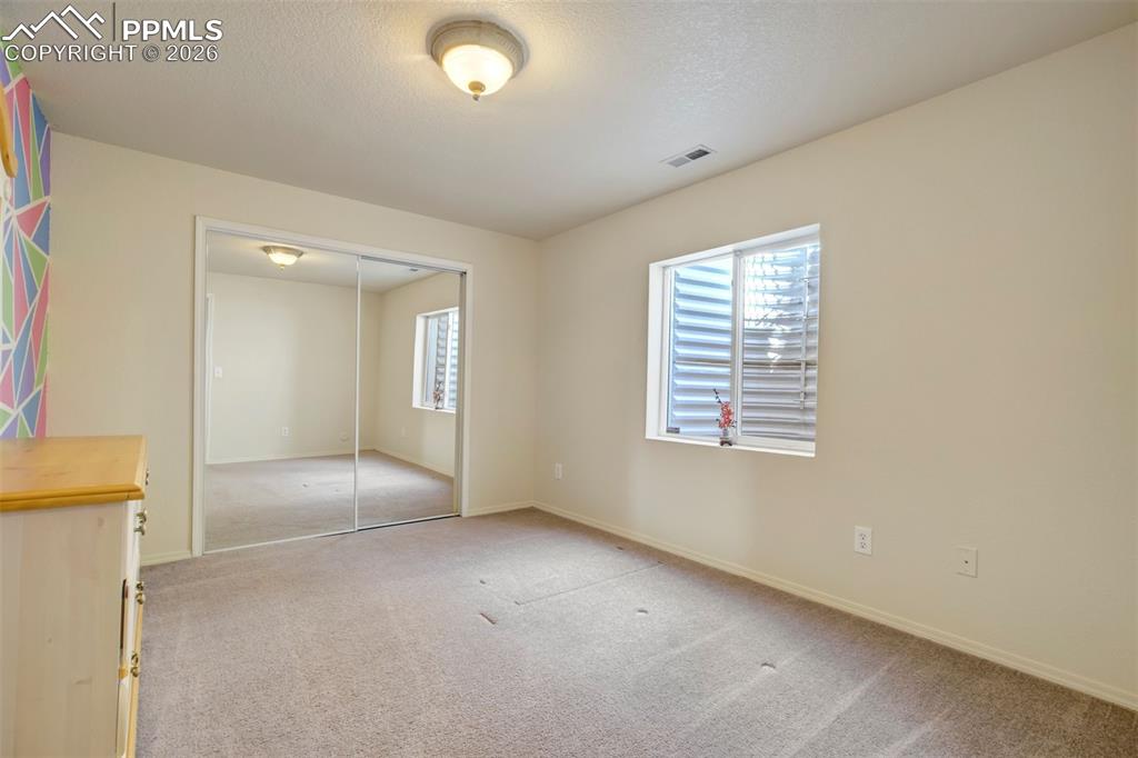 Image 38 of 50: This light-filled bedroom offers a clean, neutral palette with plush carpet