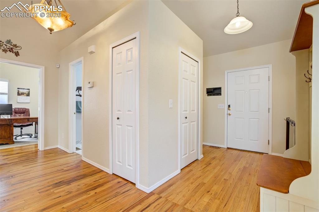 Image 4 of 50: Step inside to a welcoming entryway featuring warm wood flooring and vaulte