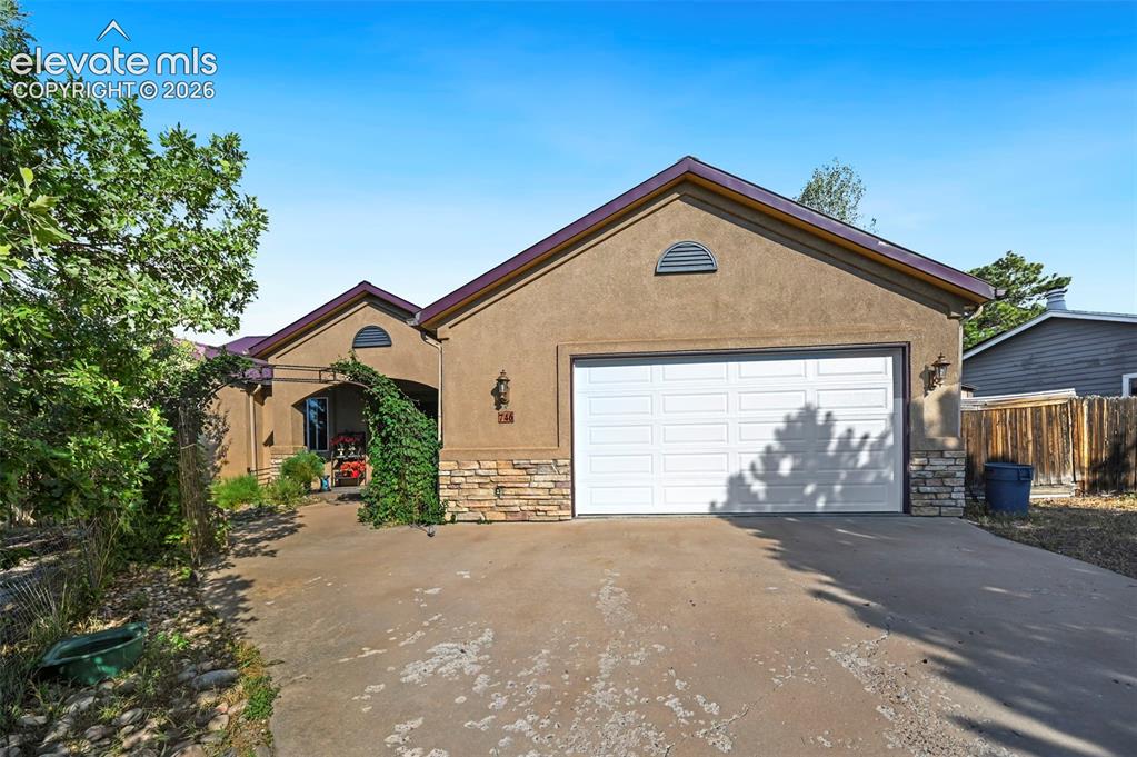 Image 1 of 43: Stucco exterior with a peaked roofline, a two-car garage, and stone accent
