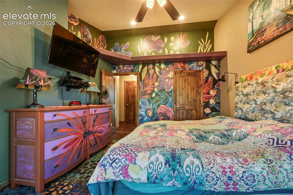 Image 14 of 43: Room featuring a vibrant floral mural wall, wood-finish doors, ceiling fan,