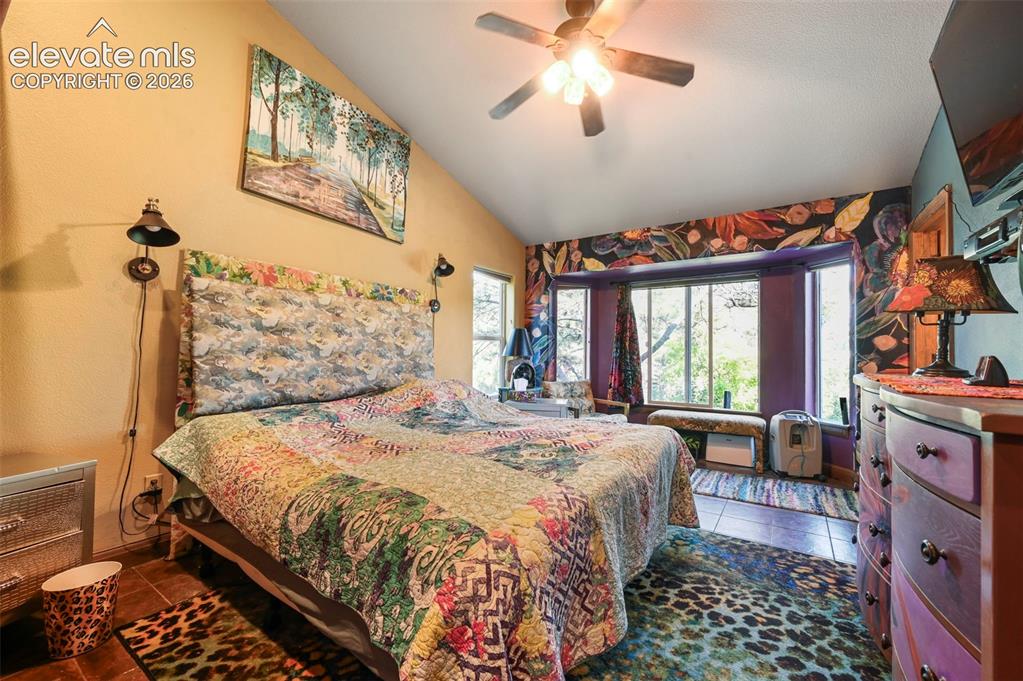Image 16 of 43: Vaulted ceiling bedroom featuring a ceiling fan with light fixture, bay win