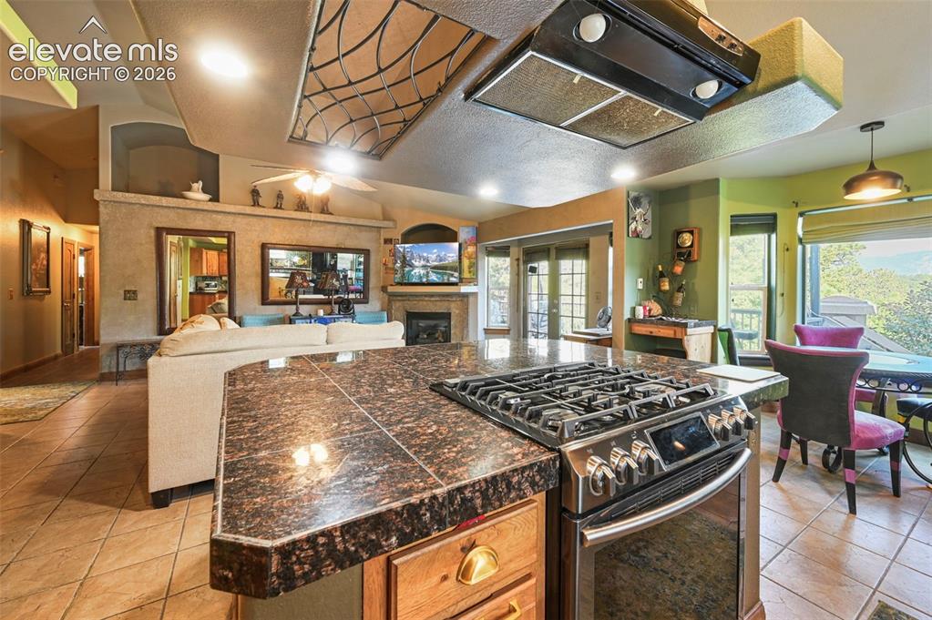 Image 2 of 43: Kitchen featuring a large central island with a dark stone countertop, an i