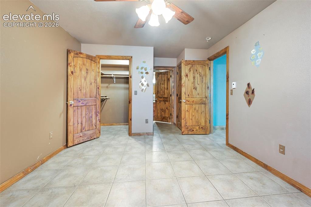Image 21 of 43: Spacious interior featuring ceramic tile flooring and natural wood doors