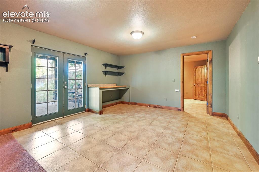 Image 23 of 43: Spacious room with large tile flooring and wood-finish baseboards