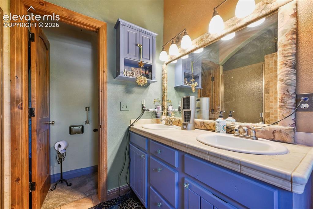 Image 26 of 43: Double vanity with individual sinks, tile countertop, and a large wall-moun