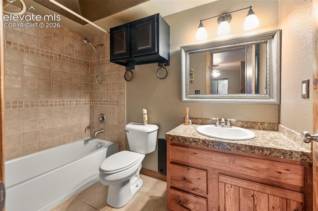 Image 28 of 43: Full bathroom featuring a white porcelain tub and toilet, neutral-toned til