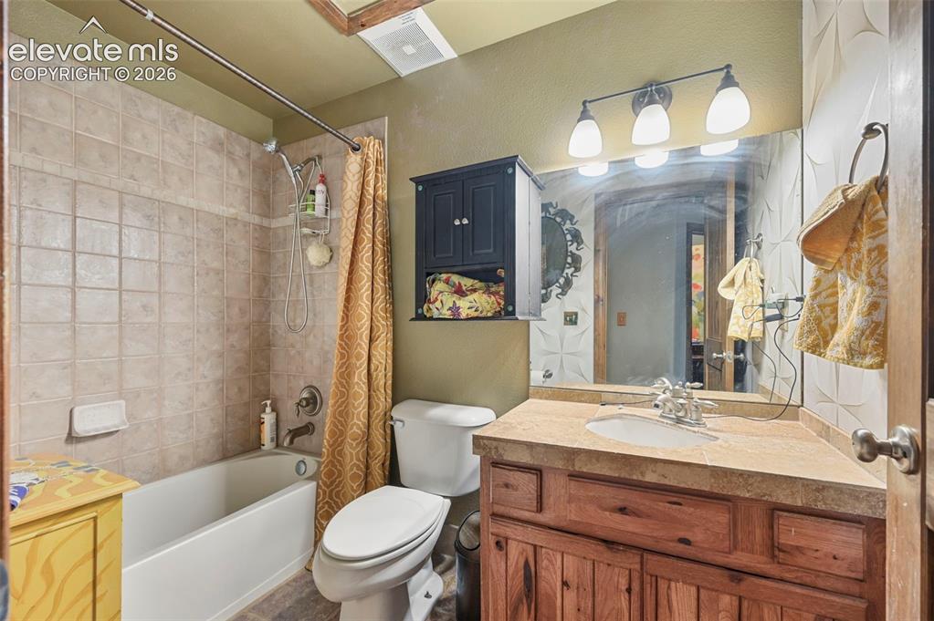 Image 29 of 43: Bathroom featuring a tiled tub-shower combination, wood-finish vanity with