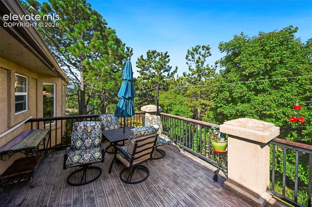 Image 30 of 43: Expansive wood-finish deck with a black metal railing and sturdy stucco-fin