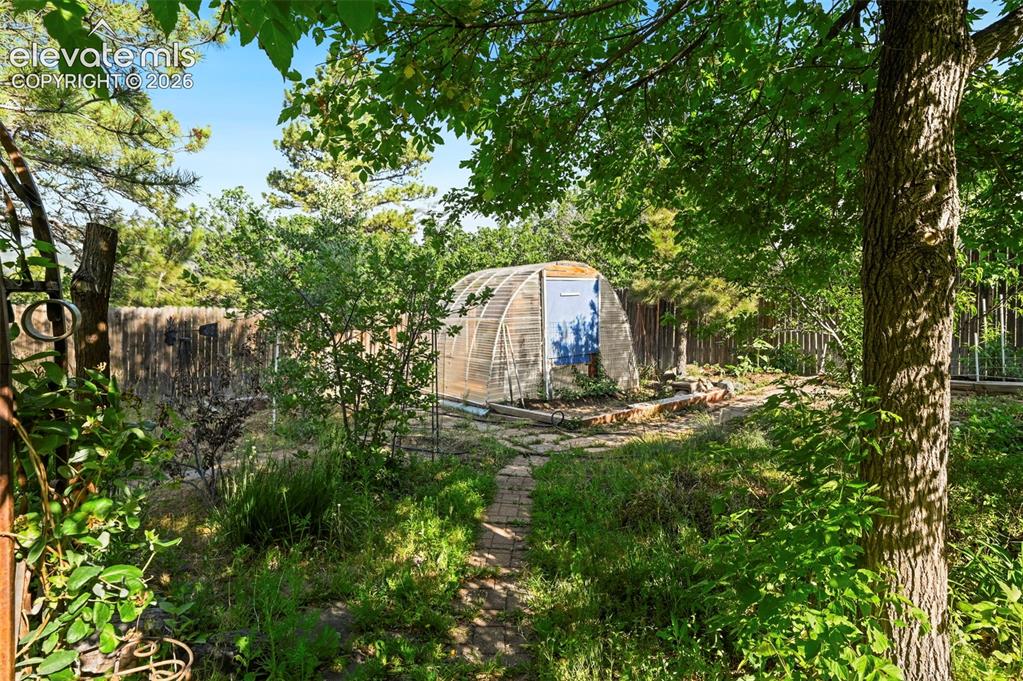 Image 31 of 43: Garden area featuring a semi-circular greenhouse structure, a stone pathway