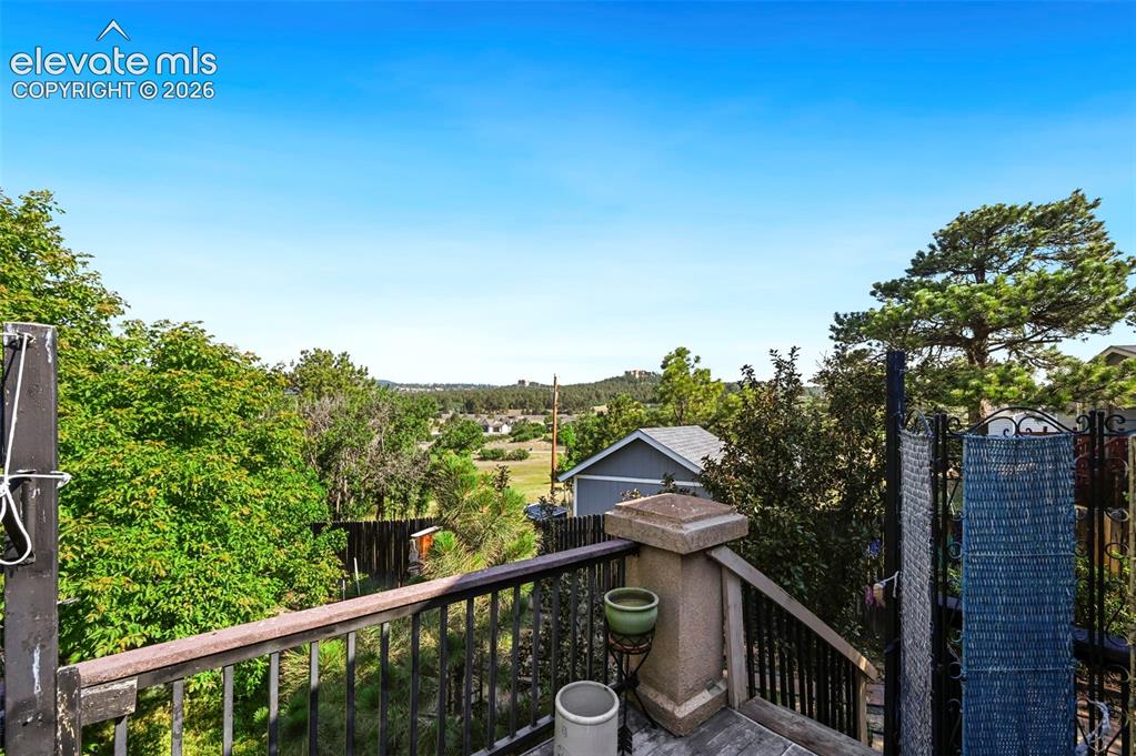 Image 33 of 43: Elevated outdoor deck featuring dark wood railing and balusters, with surro