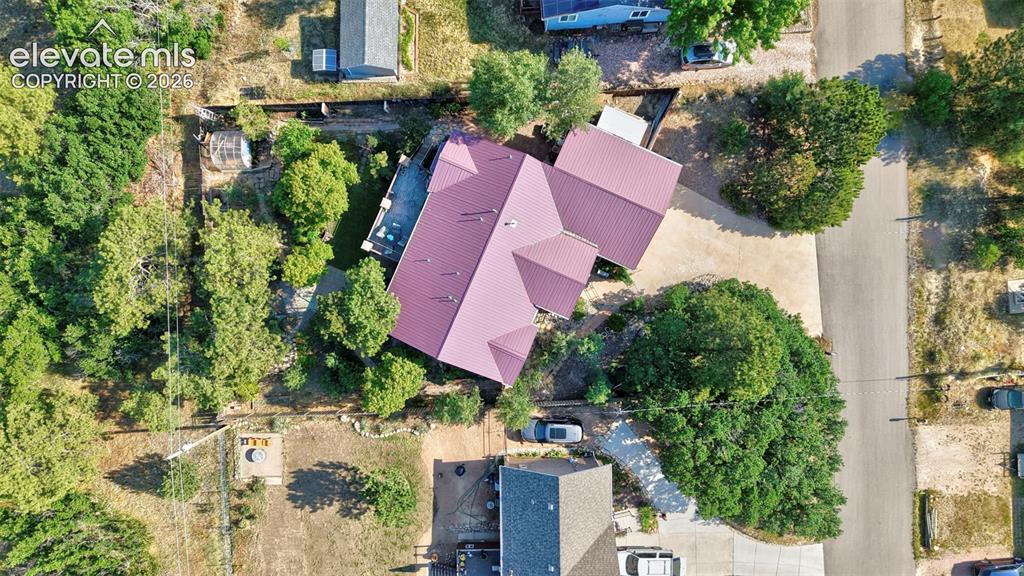 Image 41 of 43: Property featuring a vibrant red metal roof, a gravel driveway, and extensi