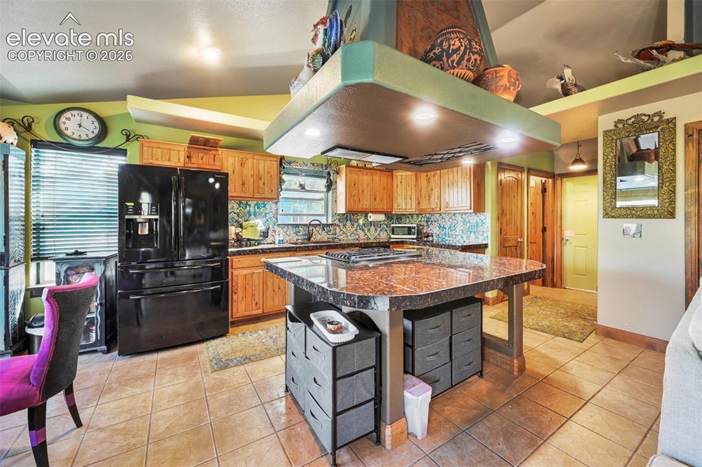 Image 8 of 43: Kitchen featuring an expansive center island with a built-in cooktop, under