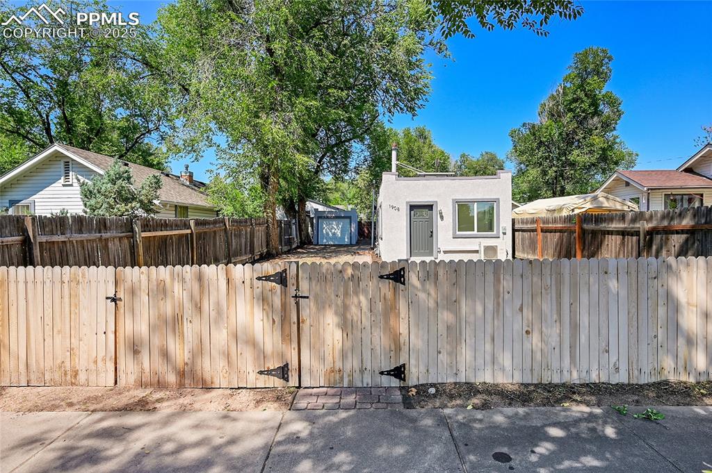 Image 18 of 30: View of front of property featuring a fenced front yard, a gate, and stucco