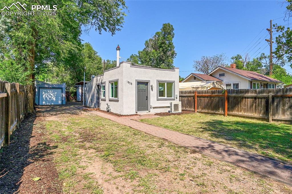 Image 21 of 30: Front of house with stucco siding, an outbuilding, a detached garage, and d