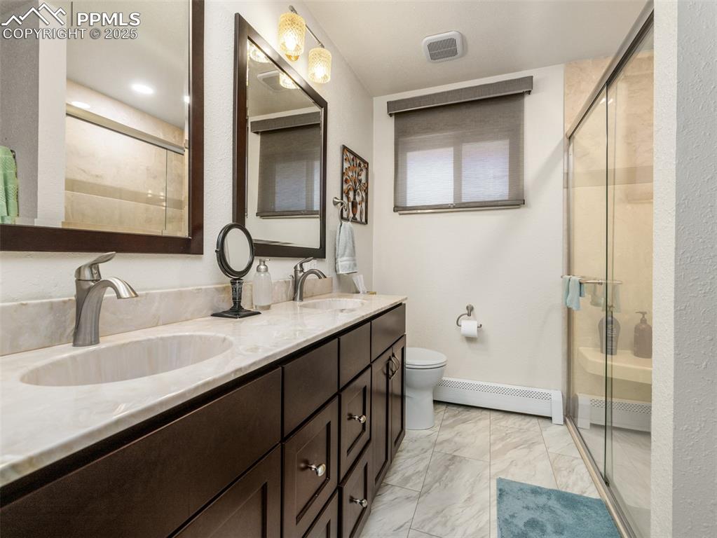 Image 16 of 41: Upgraded bathroom featuring a baseboard heating unit, a walk-in shower, dou