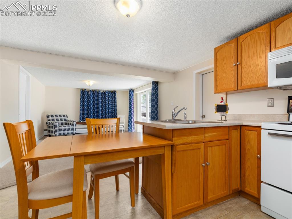 Image 18 of 41: Kitchen featuring white appliances, light countertops, wood cabinetry, a pe