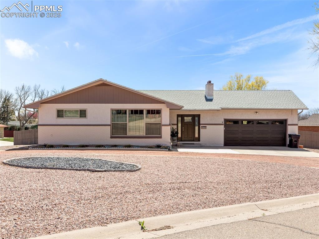 Image 2 of 41: Ranch-style home with brick and stucco siding, a chimney, an attached garag