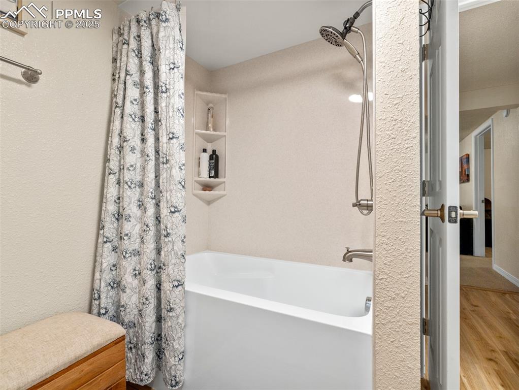 Image 24 of 41: Full bathroom with shower / bath combo, wood finished floors, and a texture