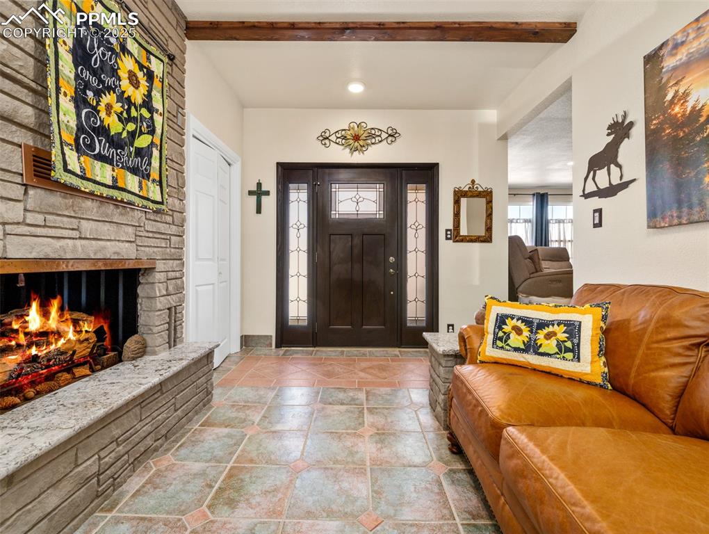 Image 4 of 41: Entrance foyer featuring a stone fireplace and beamed ceiling