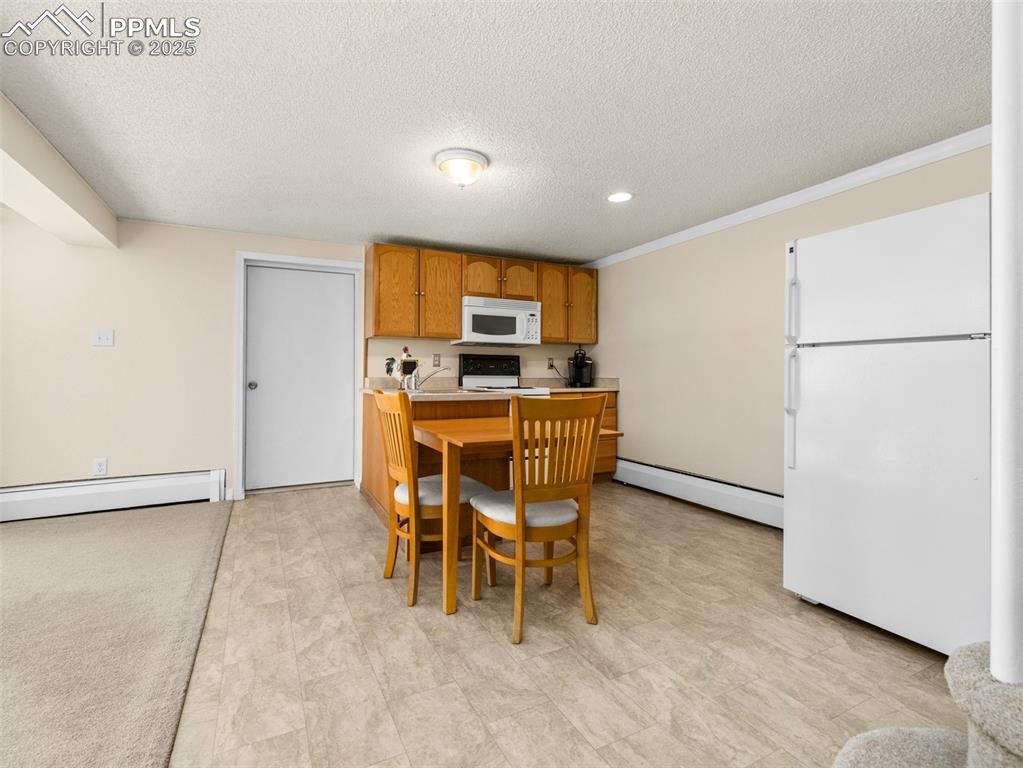 Image 9 of 41: Kitchen featuring white appliances, light countertops, a baseboard heating