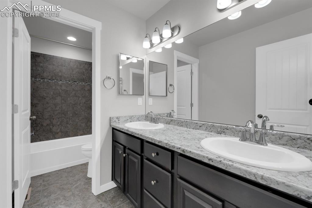 Image 18 of 40: Upper full guest bathroom featuring double vanity & tub/shower combination
