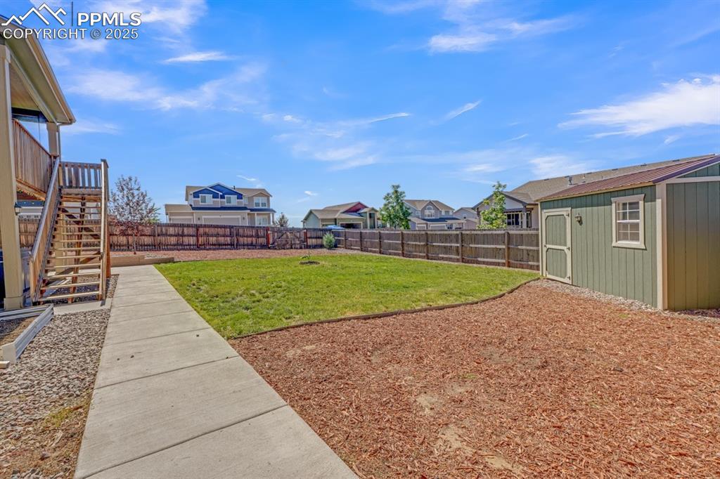 Image 30 of 40: Fenced backyard features a storage shed, grass and concrete walkway as well