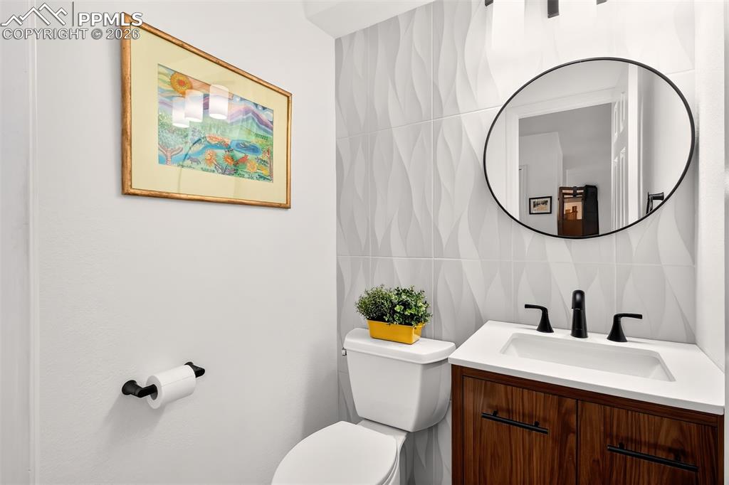 Image 14 of 36: Updated main level half bath with new vanity and new decorative tiled wall.