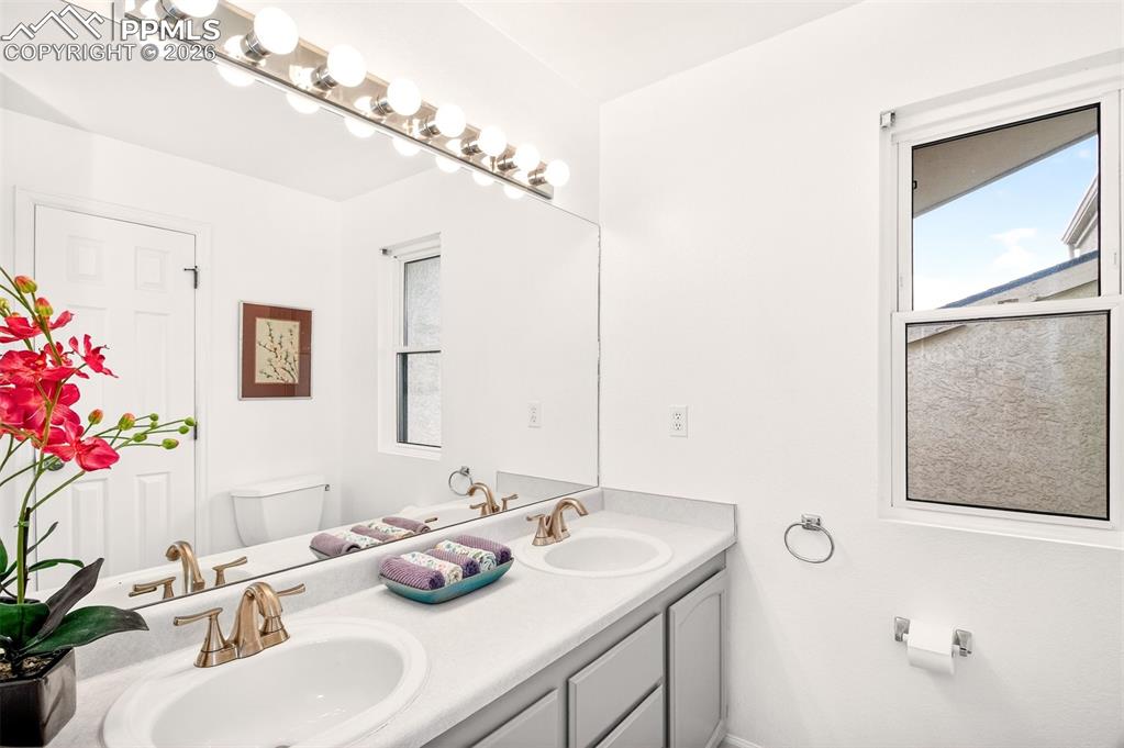 Image 18 of 32: Primary ensuite with double sinks and a window offering natural light.