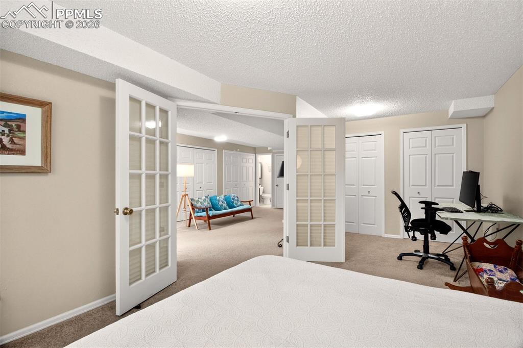 Image 27 of 32: Another view of the finished basement bedroom with charming french doors.