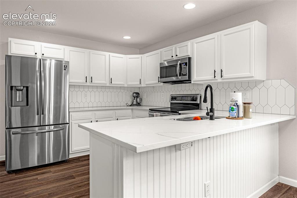 Image 10 of 35: Kitchen featuring white cabinetry, solid-surface countertops, a geometric-p