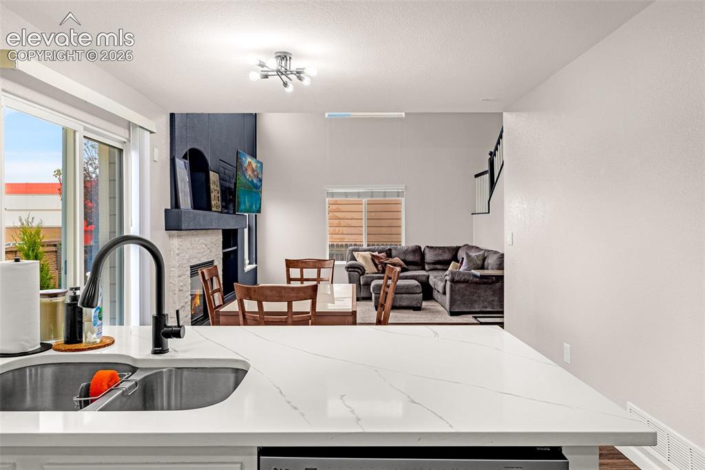 Image 13 of 35: Kitchen featuring a white stone-look countertop, undermount stainless steel