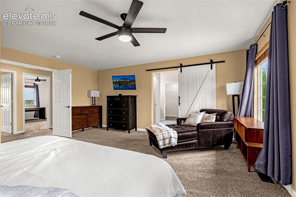 Image 19 of 35: Spacious room featuring carpeting, a white sliding barn door, and a modern 