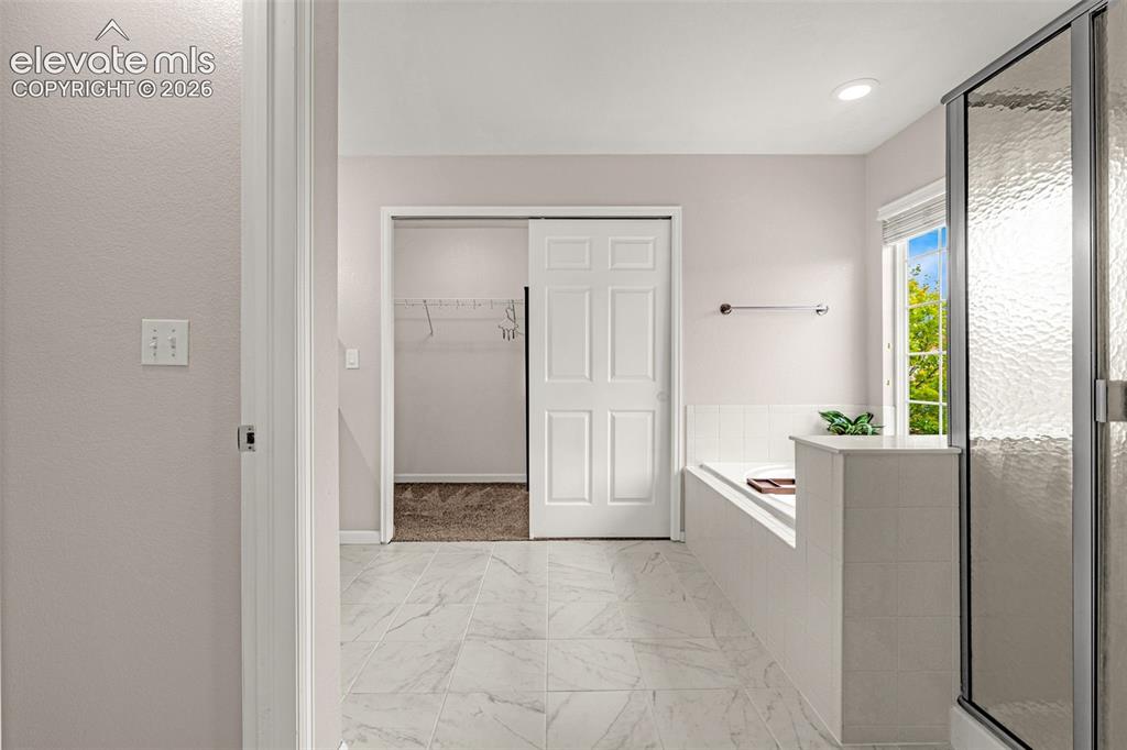 Image 20 of 35: Bathroom featuring tiled flooring, a built-in soaking tub with a tiled surr