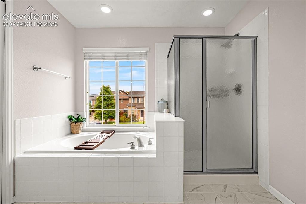 Image 21 of 35: Soaking tub with a tile-surround deck, glass-enclosed shower, tile flooring